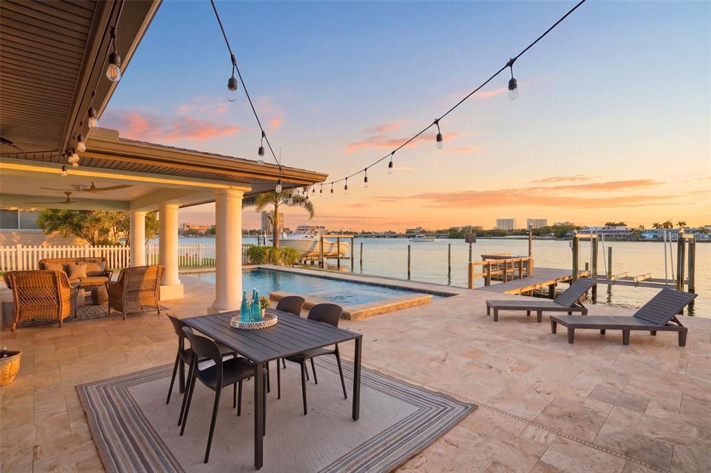 A patio with a dining set, lounge chairs, and a pool overlooking a waterfront view — 7172 S SHORE DRIVE S, ST PETERSBURG, FL