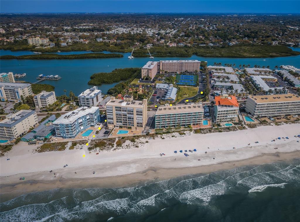 An aerial view shows several beachfront condominium buildings with swimming pools along a sandy shore — 19451 GULF BOULEVARD UNIT 301, INDIAN SHORES, FL