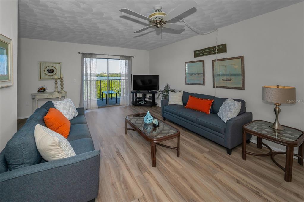 A living room features two blue sofas, a coffee table, and a balcony with water views — 19451 GULF BOULEVARD UNIT 301, INDIAN SHORES, FL