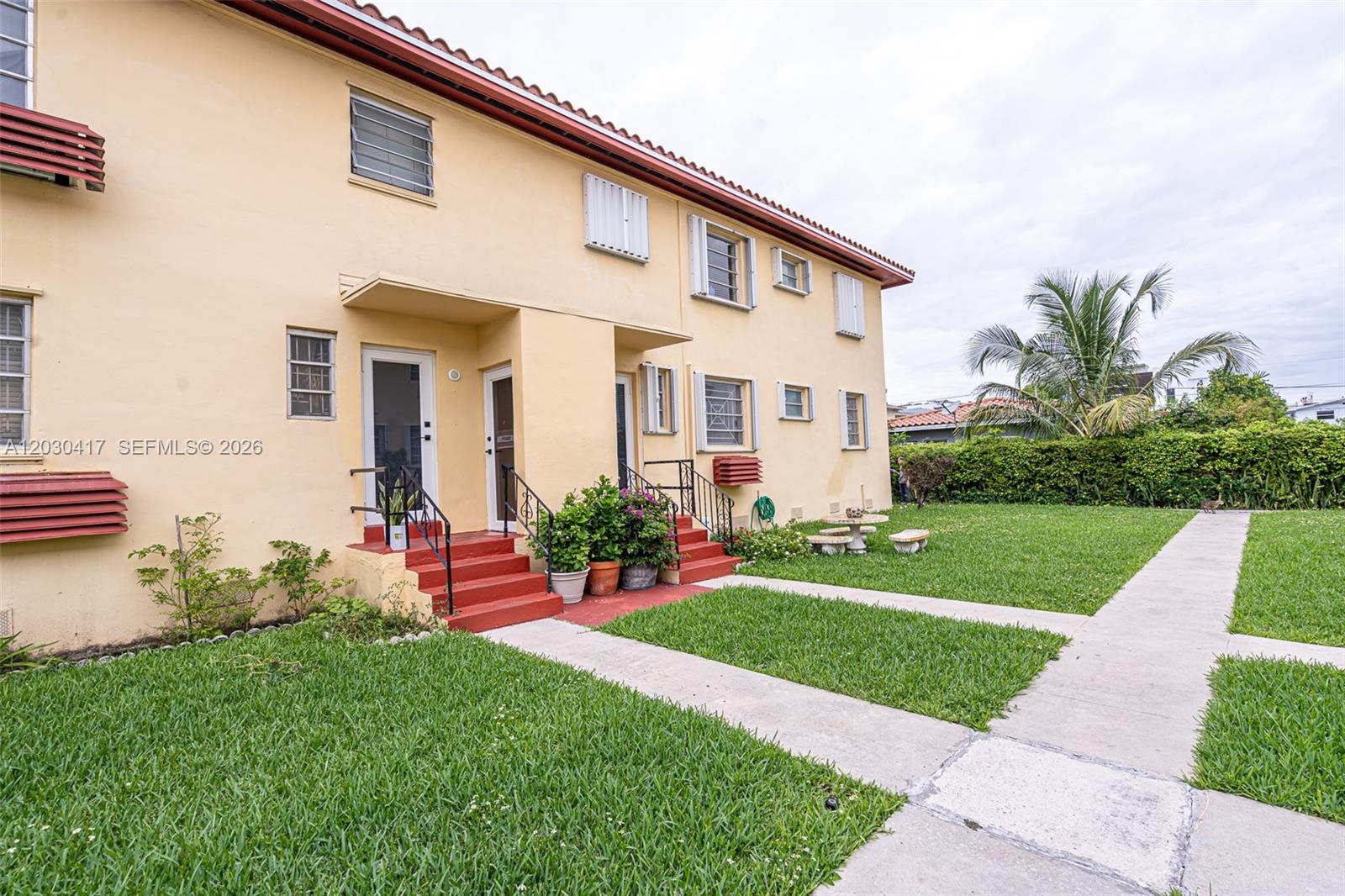 A two-story yellow apartment building features red stairs and a shared grassy courtyard — 637 SW 11th St # 6W, Miami FL 33129, MIAMI, FL