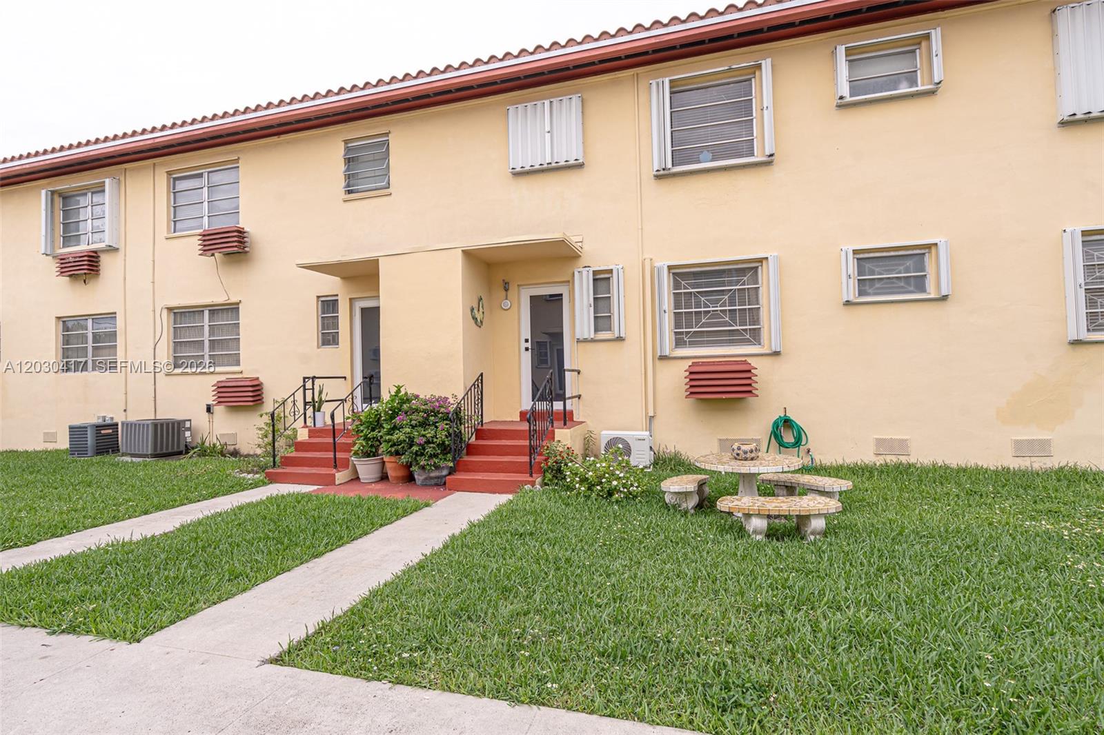 The exterior of a two-story apartment building features yellow stucco walls and red-painted concrete steps — 637 SW 11th St # 6W, Miami FL 33129, MIAMI, FL