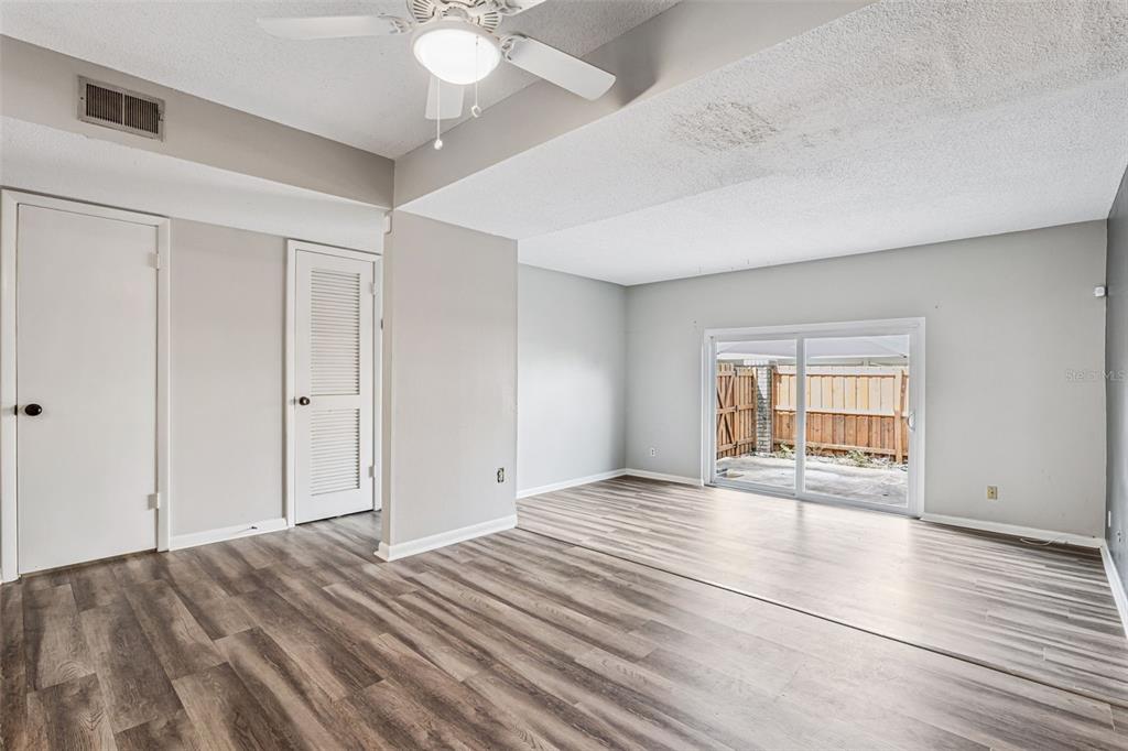 An empty room with light gray walls, wood-look flooring, a ceiling fan, and sliding glass doors — 200 SAINT ANDREWS BOULEVARD UNIT 2904, WINTER PARK, FL