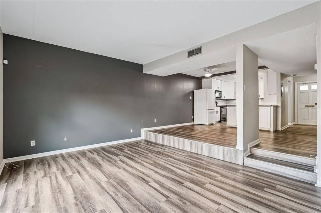 A living room with gray walls and wood-look flooring features a raised kitchen area — 200 SAINT ANDREWS BOULEVARD UNIT 2904, WINTER PARK, FL