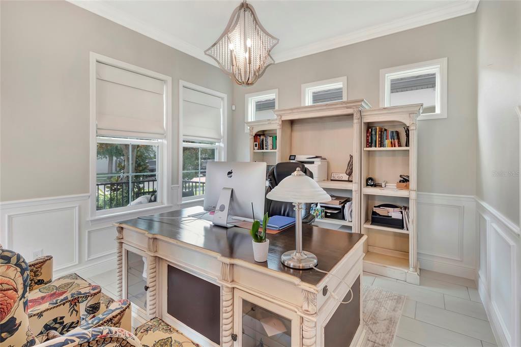 A home office features a large wooden desk, built-in shelving, and two patterned armchairs — 1664 HOLCOMB CREEK ST., WINTER GARDEN, FL
