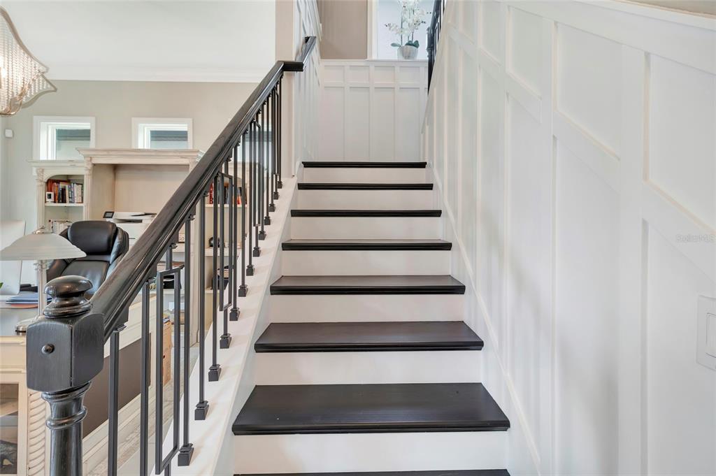 A staircase with dark wood treads and white risers features a black metal railing — 1664 HOLCOMB CREEK ST., WINTER GARDEN, FL