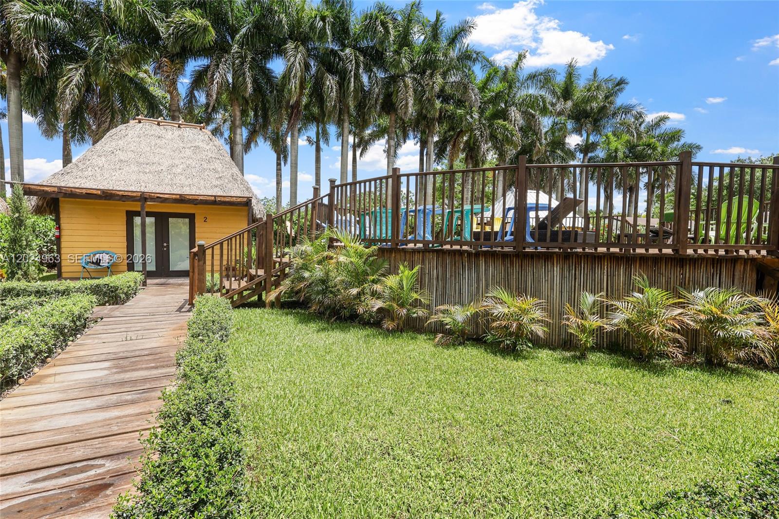 A wooden walkway leads to a yellow hut with a thatched roof near a deck — 14701 SW 199th Ave, Miami FL 33196, MIAMI, FL