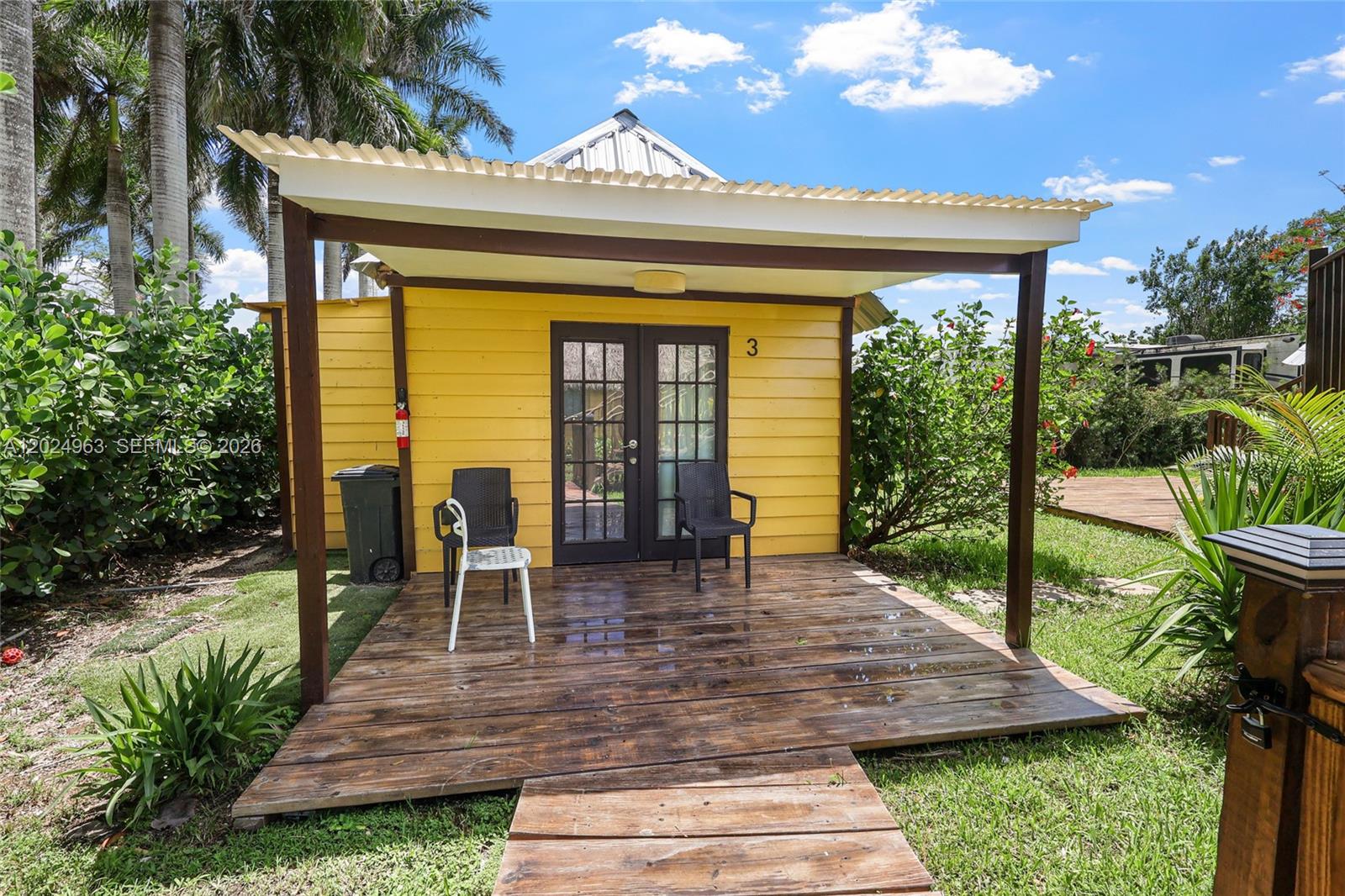 A yellow cabin with a wooden deck and a corrugated metal roof stands outdoors — 14701 SW 199th Ave, Miami FL 33196, MIAMI, FL