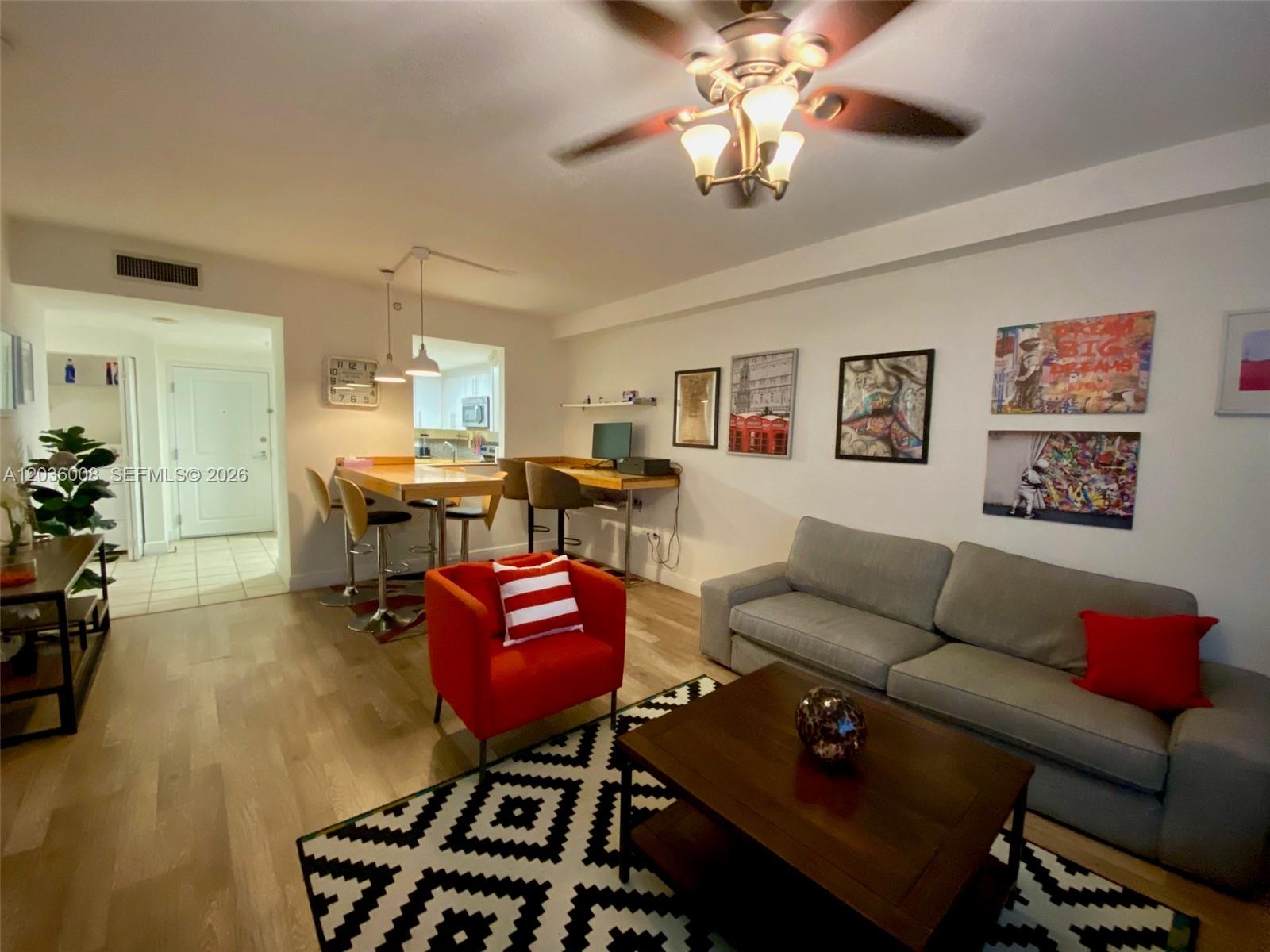 A living room features a grey sofa, red armchair, wooden coffee table, and breakfast bar — 1250 S Miami Ave # 1312, Miami FL 33130, MIAMI, FL