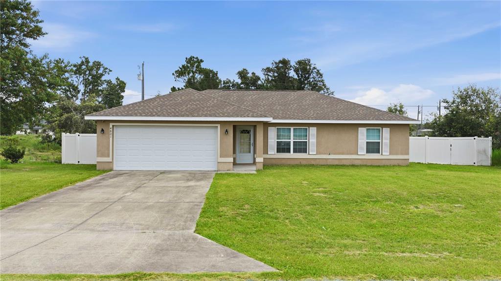 A single-story house with a tan stucco exterior, a two-car garage, and a concrete driveway — 4801 145TH PLACE, OCALA, FL