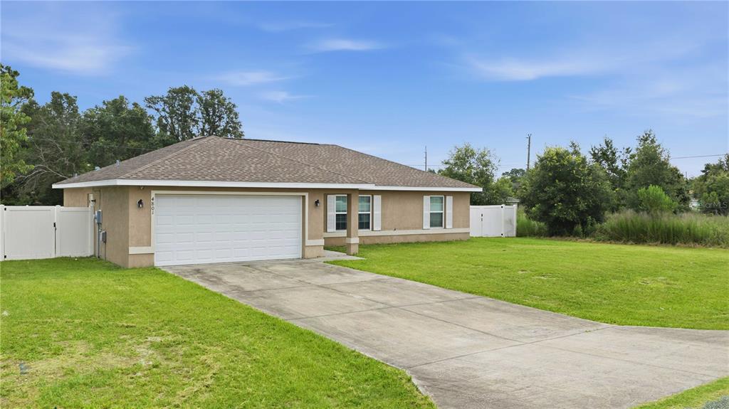 A single-story house with a tan stucco exterior, a two-car garage, and a concrete driveway — 4801 145TH PLACE, OCALA, FL