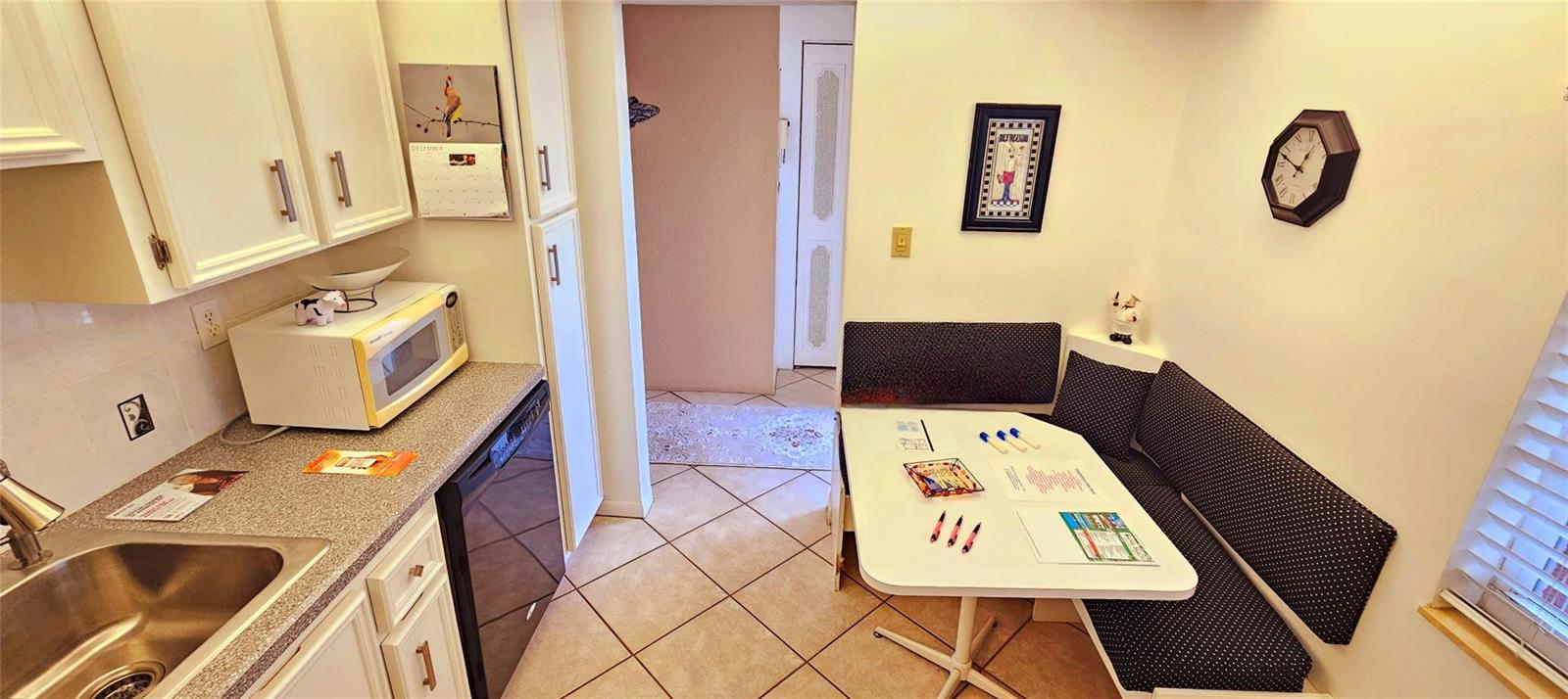 A kitchen features white cabinets, a microwave, a sink, and a small dining nook — 121 SE 3rd Avenue # 106, Dania Beach FL 33004, DANIA BEACH, FL
