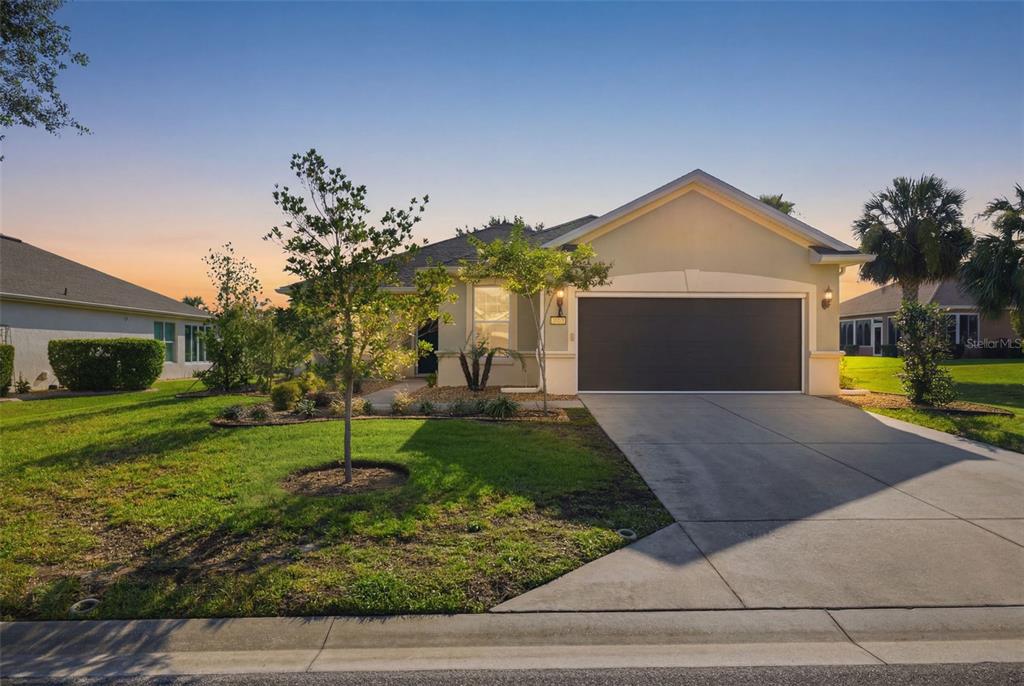 A single-story house with a two-car garage and a landscaped front yard at sunset — 6951 SW 94TH COURT, OCALA, FL