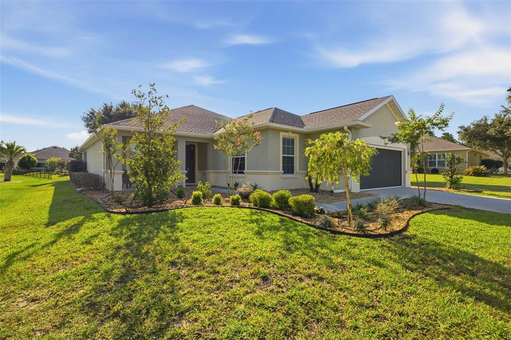 A single-story house with a beige stucco exterior, a two-car garage, and a landscaped lawn — 6951 SW 94TH COURT, OCALA, FL