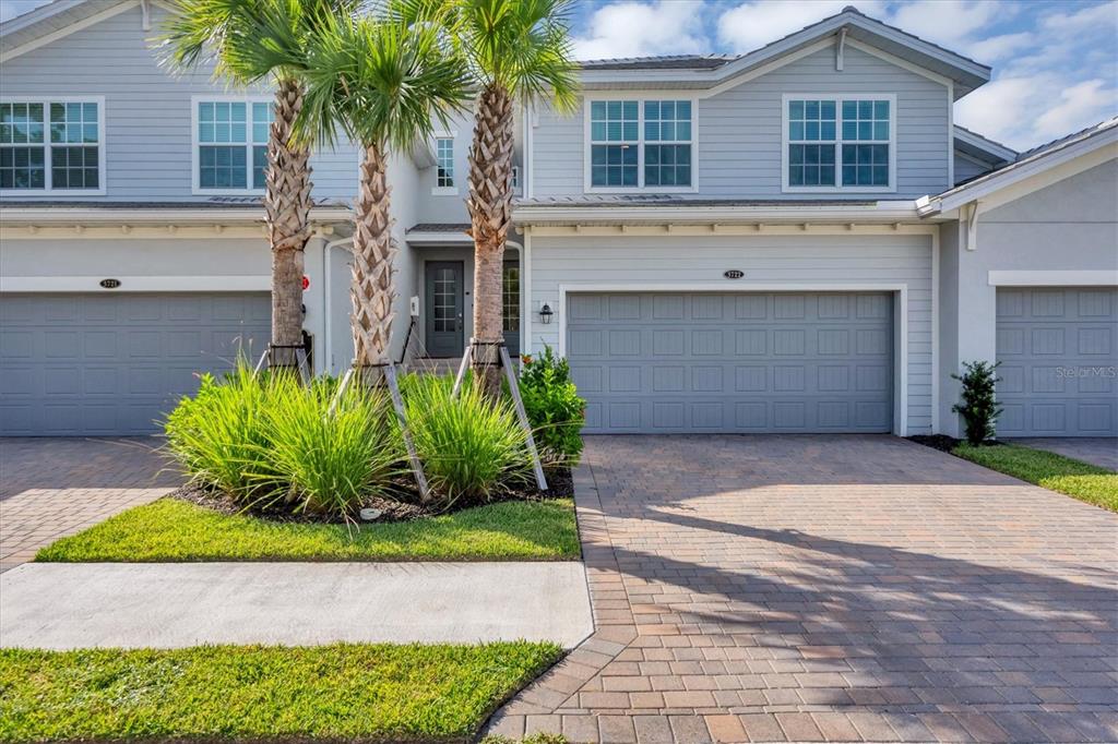 A two-story townhouse exterior features light blue siding, a paved driveway, and palm trees — 14680 SYCAMORE COURT UNIT 3722, PUNTA GORDA, FL