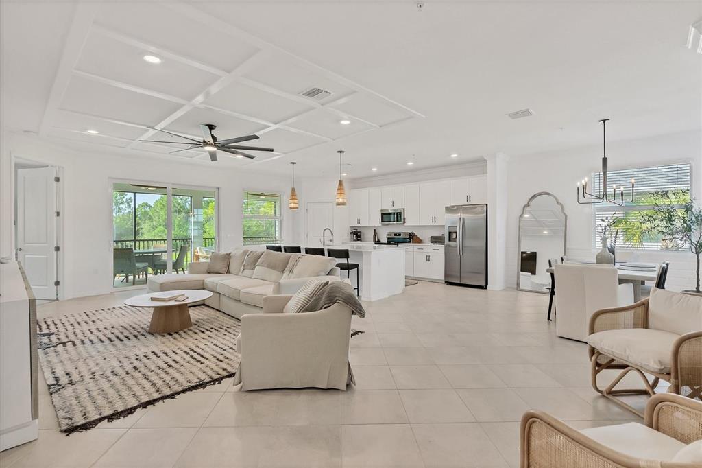 An open-concept living room and kitchen with white cabinetry, tile floors, and a coffered ceiling — 14680 SYCAMORE COURT UNIT 3722, PUNTA GORDA, FL