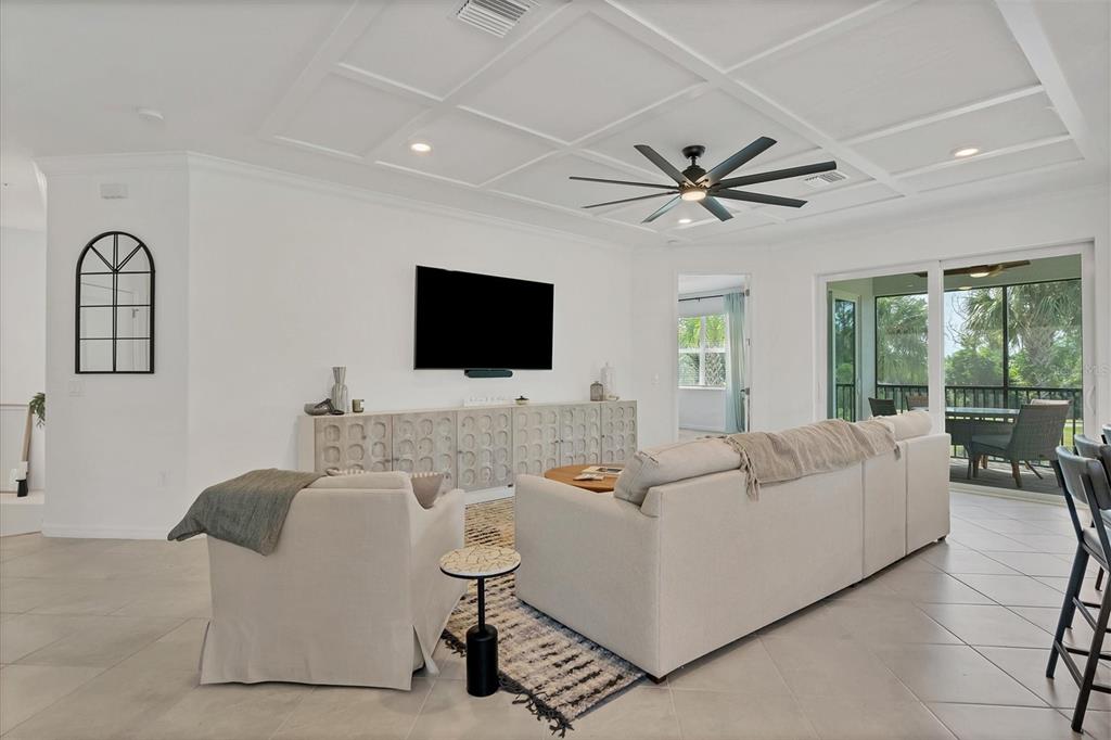 A living room with a coffered ceiling, ceiling fan, large sofa, and sliding glass doors — 14680 SYCAMORE COURT UNIT 3722, PUNTA GORDA, FL