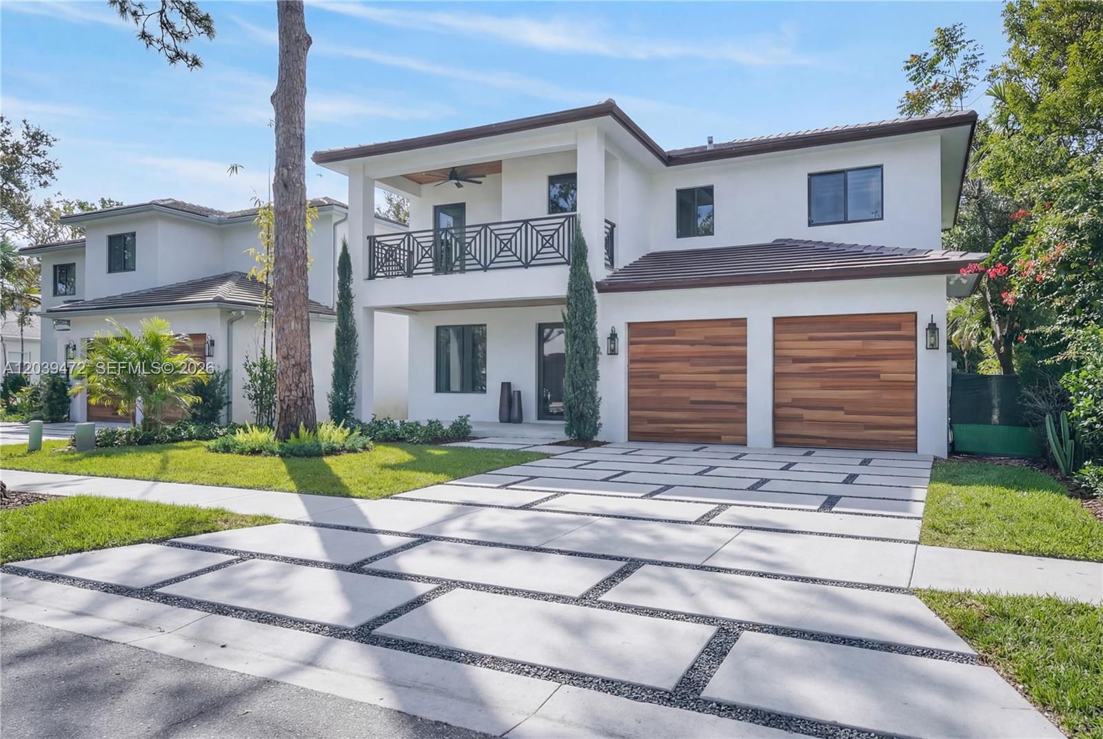 A two-story white house with a modern driveway, wooden garage doors, and a balcony — 7212 SW 52nd Ct, Miami FL 33143, MIAMI, FL