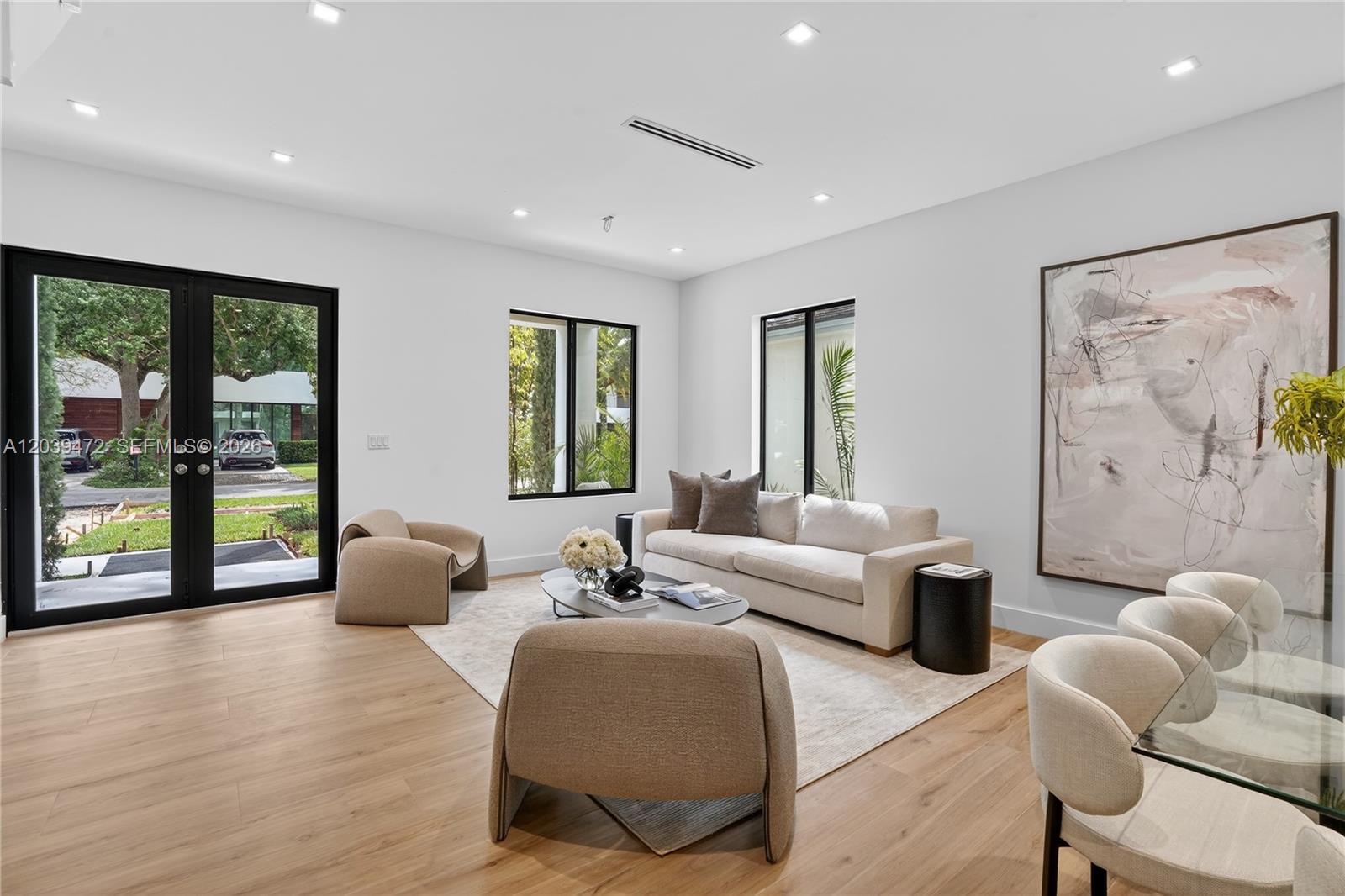 A bright living room features light wood floors, a neutral sofa, and glass patio doors — 7212 SW 52nd Ct, Miami FL 33143, MIAMI, FL