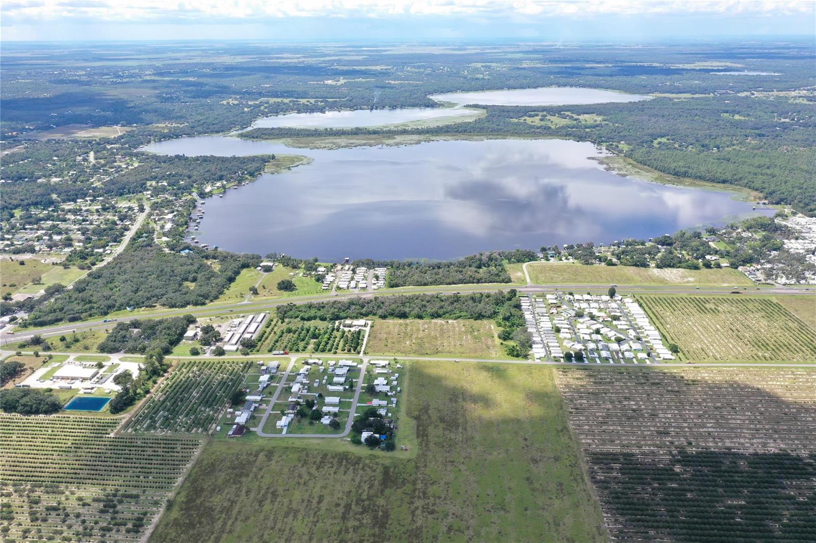 An aerial view shows a large lake surrounded by residential neighborhoods and agricultural fields — 11400 Us-27, Sebring FL 33876, SEBRING, FL