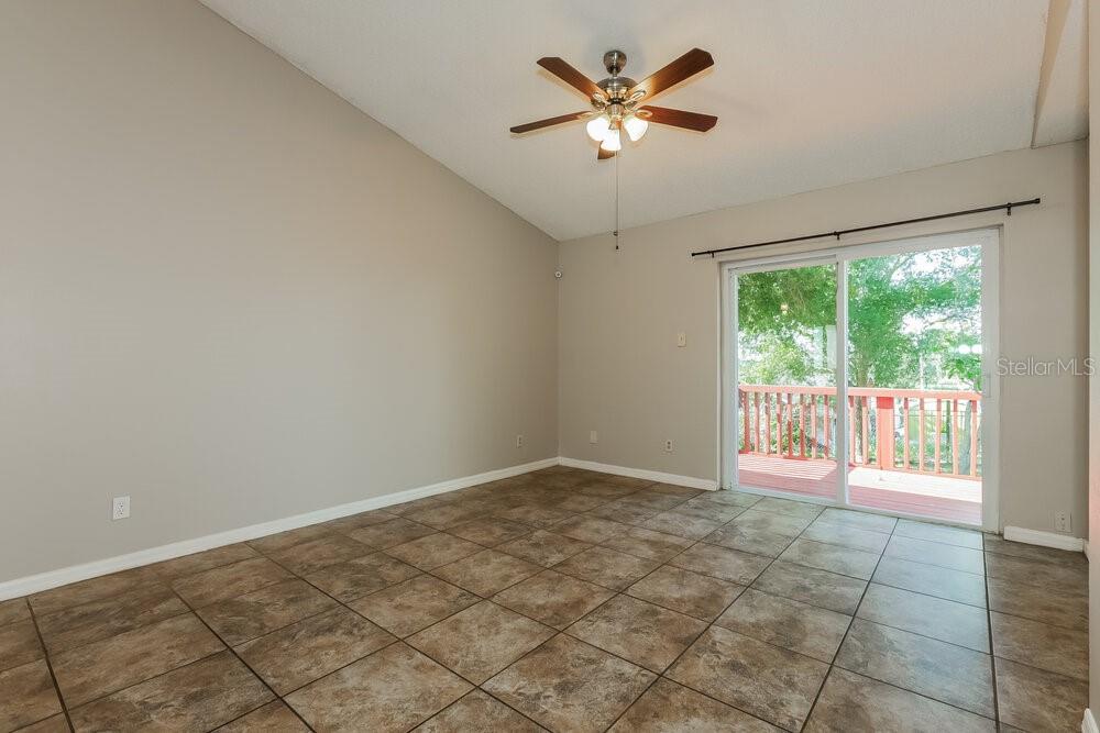 An empty room with tan walls, tiled flooring, a ceiling fan, and a sliding glass door — 1424 COVINGTON COURT, LAKE WALES, FL