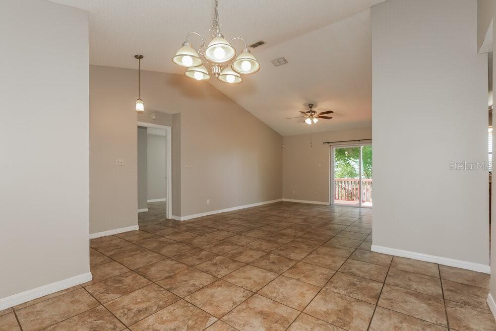An open-concept living area features vaulted ceilings, tile flooring, and a sliding glass door — 1424 COVINGTON COURT, LAKE WALES, FL