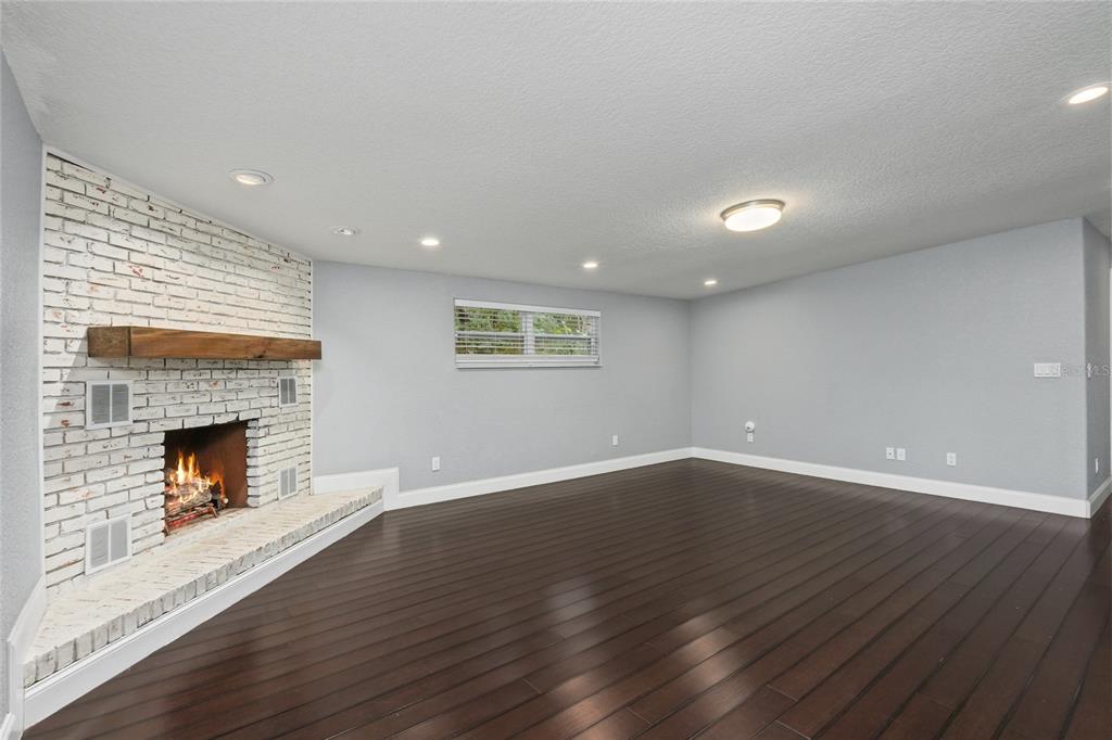 A living room features dark hardwood floors, light gray walls, and a white brick fireplace — 1520 S CHURCH AVENUE, TAMPA, FL