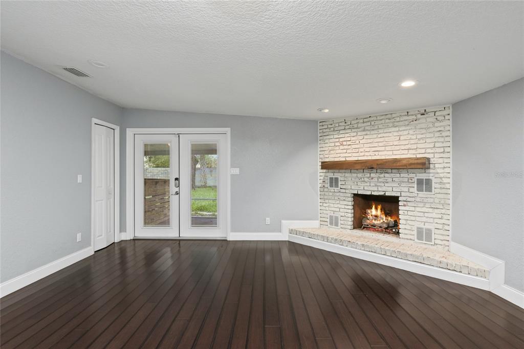A living room features dark wood floors, light gray walls, and a corner white brick fireplace — 1520 S CHURCH AVENUE, TAMPA, FL
