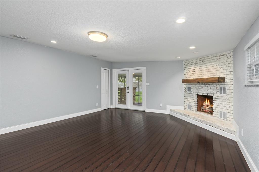 A living room with dark wood floors, light gray walls, and a white brick fireplace — 1520 S CHURCH AVENUE, TAMPA, FL