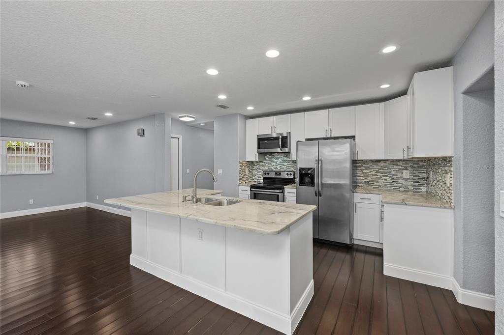 A kitchen with white cabinets, stainless steel appliances, a stone island, and dark wood floors — 1520 S CHURCH AVENUE, TAMPA, FL
