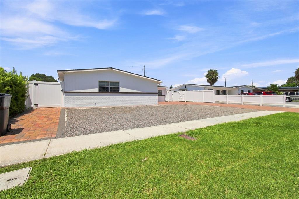 A single-story house with a white brick exterior, a gravel front yard, and a brick driveway — 6033 AMBASSADOR DRIVE, TAMPA, FL