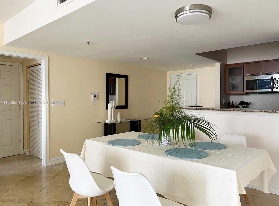A dining area features a table with chairs, a centerpiece, and an adjacent kitchen counter — 2080 S Ocean Dr # 806, Hallandale Beach FL 33009, HALLANDALE BEACH, FL