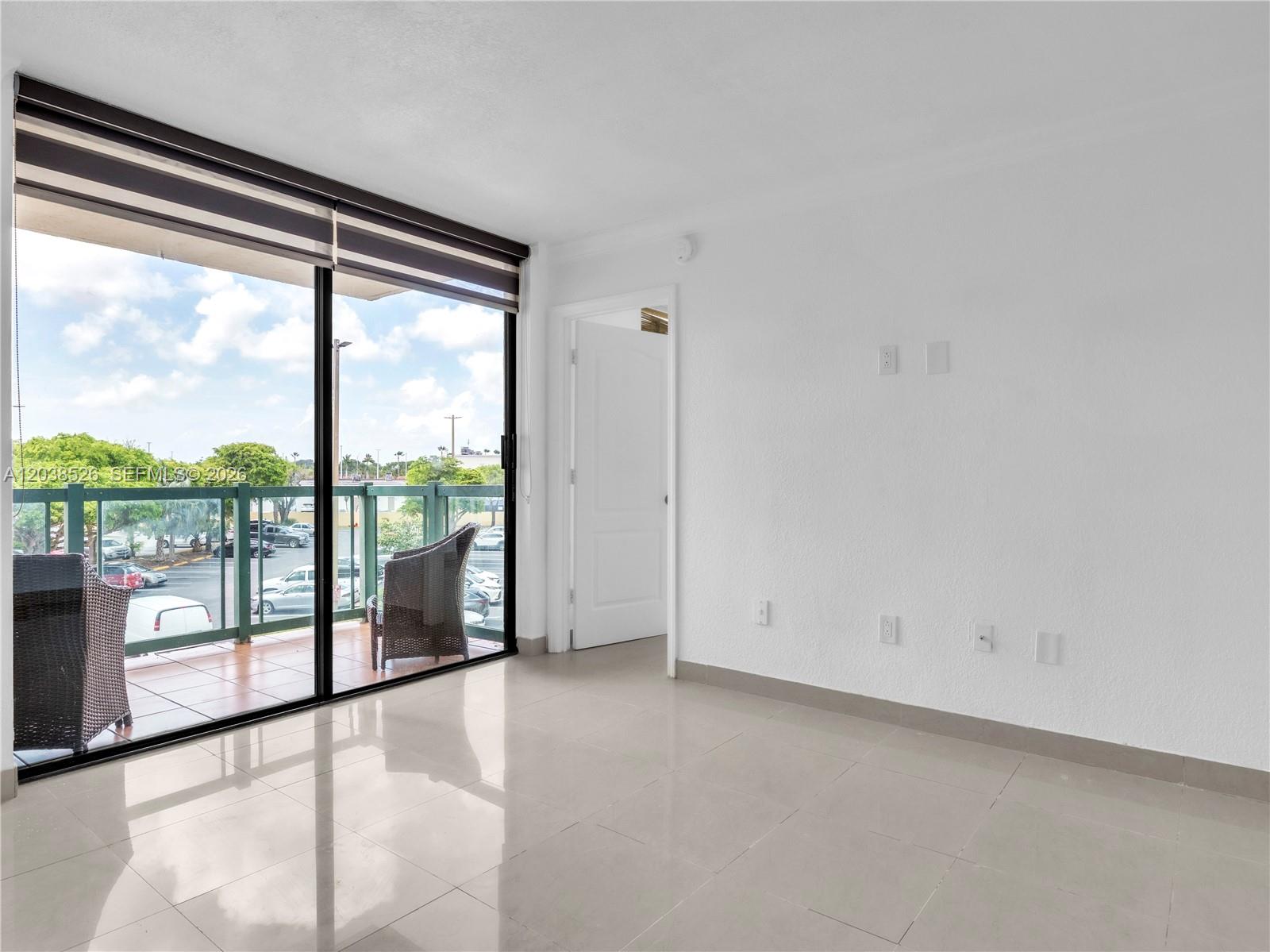 An empty room features white walls, tile flooring, a sliding glass door, and a balcony — 2075 SW 122nd Ave # 304, Miami FL 33175, MIAMI, FL