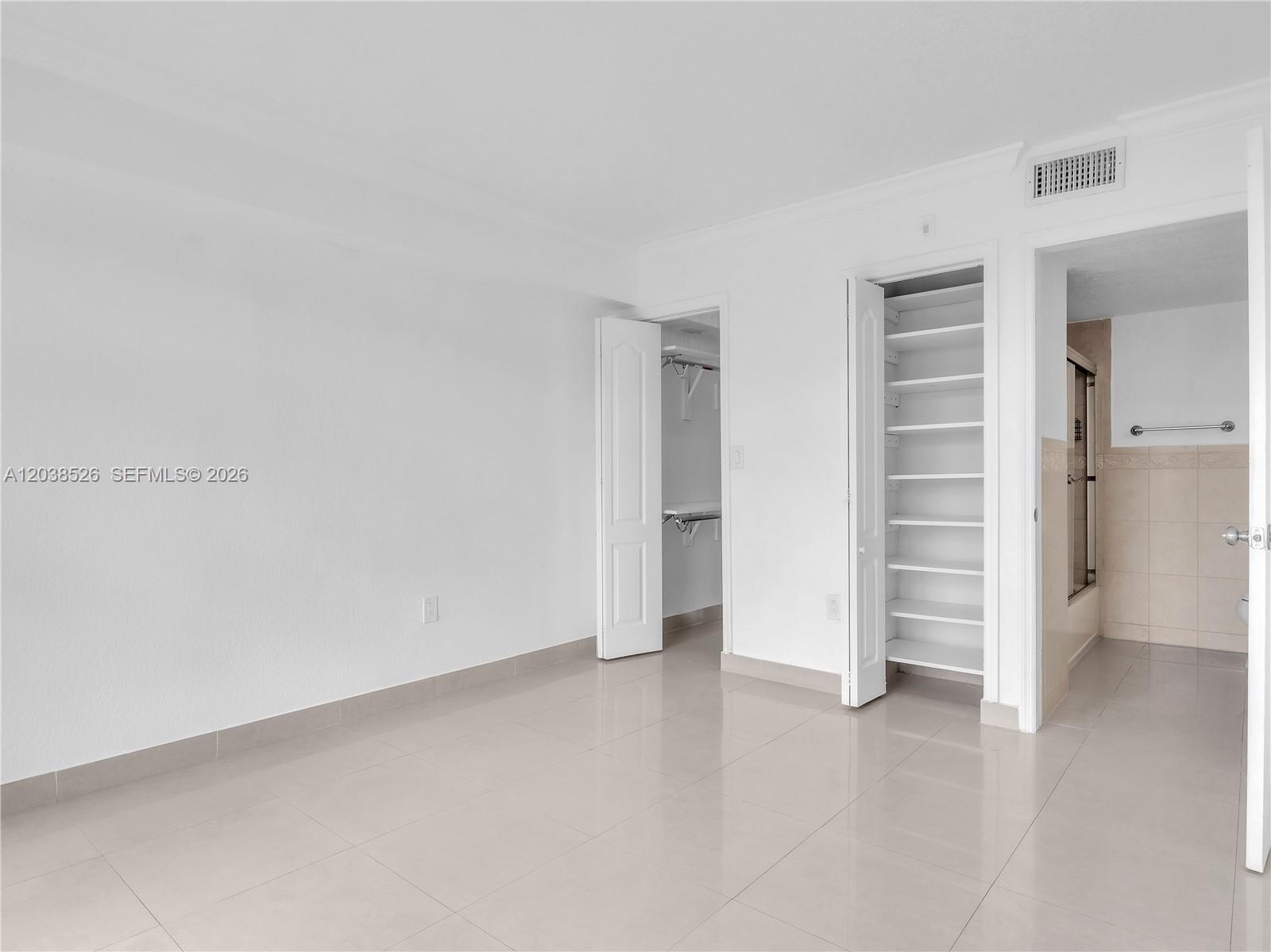 A room with white walls, tiled floors, two open closets, and an attached bathroom — 2075 SW 122nd Ave # 304, Miami FL 33175, MIAMI, FL