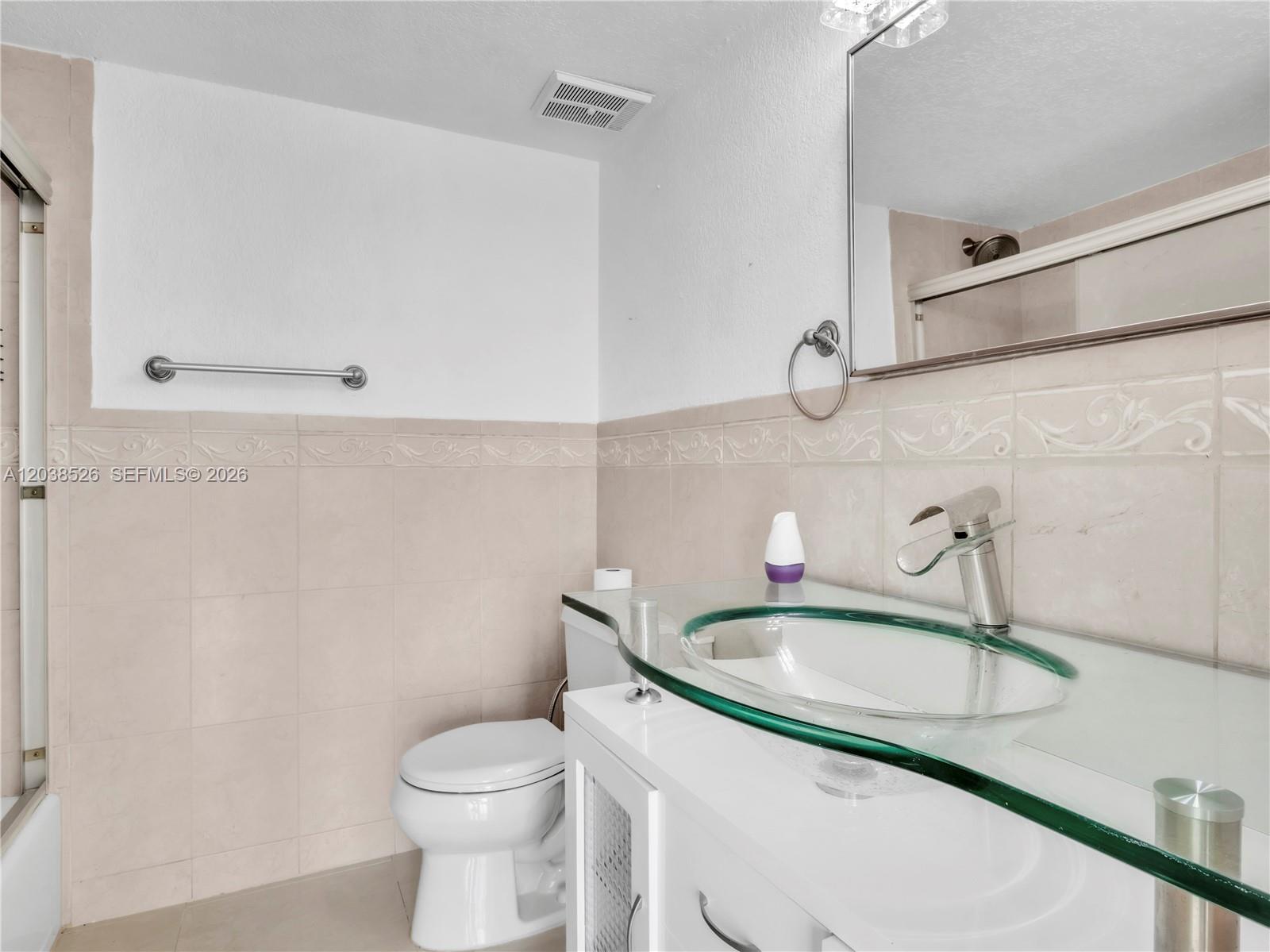A bathroom features a glass vessel sink, white vanity, toilet, and beige tiled walls — 2075 SW 122nd Ave # 304, Miami FL 33175, MIAMI, FL
