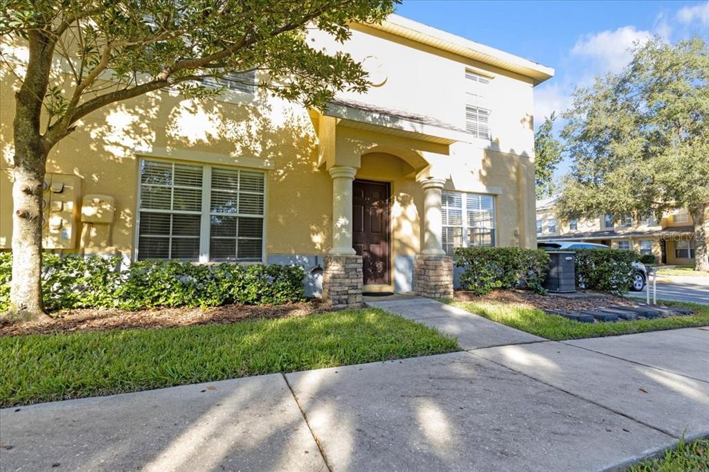 A two-story tan stucco townhouse with a covered entryway and stone-based columns — 37554 DALIHA TERRACE, ZEPHYRHILLS, FL