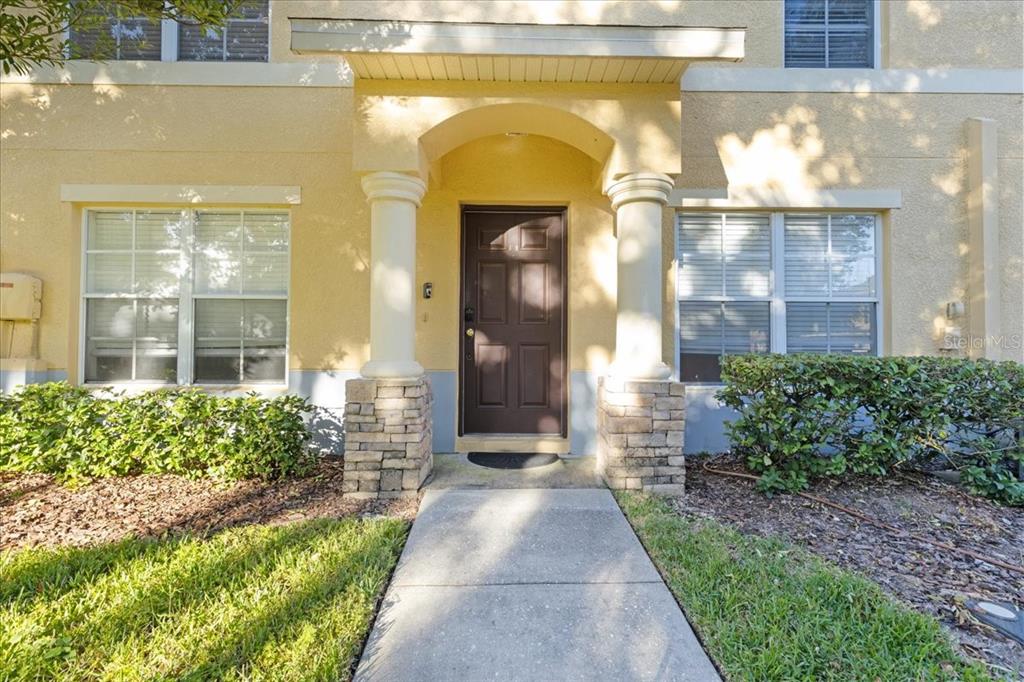 A front entrance with a brown door, two columns, and stone bases on a yellow building — 37554 DALIHA TERRACE, ZEPHYRHILLS, FL