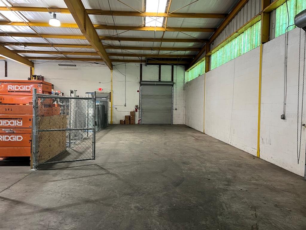 An industrial warehouse space features a concrete floor, high ceilings, and a roll-up door — 6625 ANDERSON ROAD, TAMPA, FL