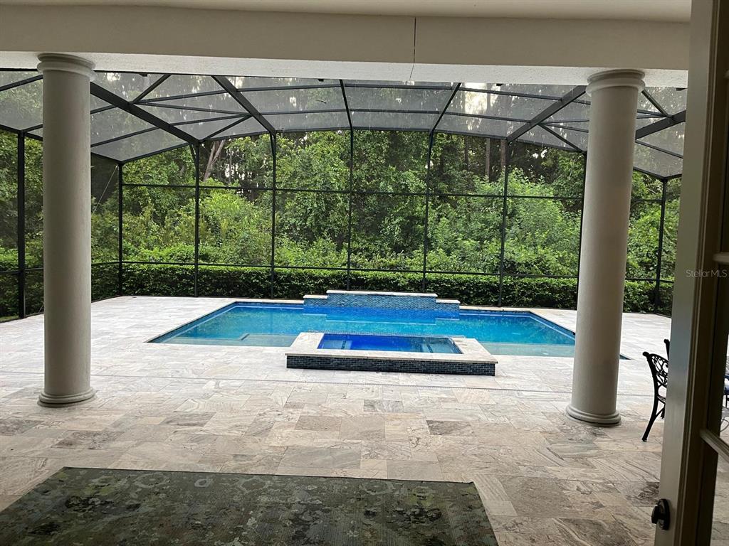 A screened-in patio features a swimming pool, a raised spa, and stone tile flooring — 6354 CARTMEL LANE, WINDERMERE, FL