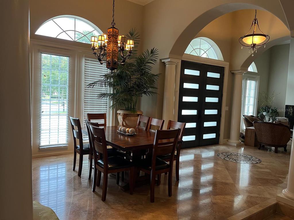 A dining room with a wooden table, chairs, and a chandelier on a tiled floor — 6354 CARTMEL LANE, WINDERMERE, FL