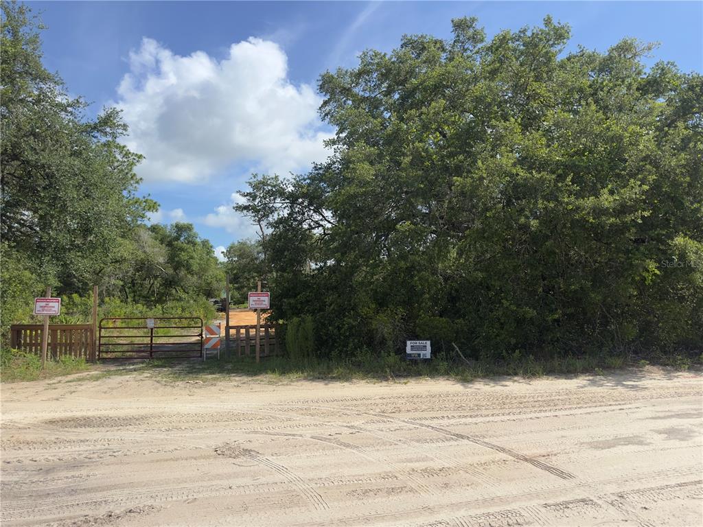 A dirt road leads to a gated entrance of a wooded, undeveloped lot for sale — 8389 SW 155TH STREET, DUNNELLON, FL