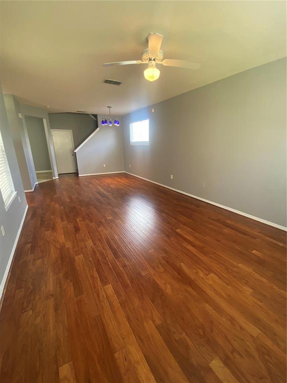An empty room features hardwood floors, a ceiling fan, and a staircase leading upstairs — 4009 SAND PALM COURT, TAMPA, FL