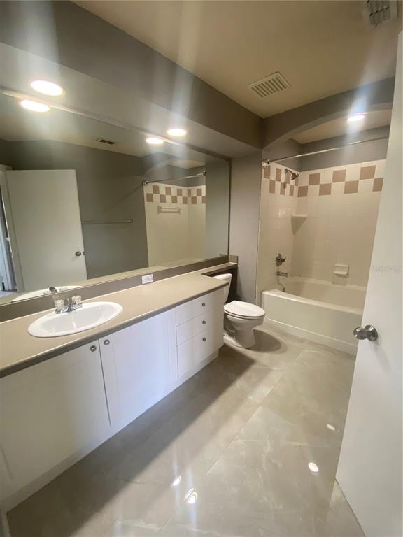 A bathroom features a white vanity with a sink, a toilet, and a tiled tub — 4009 SAND PALM COURT, TAMPA, FL