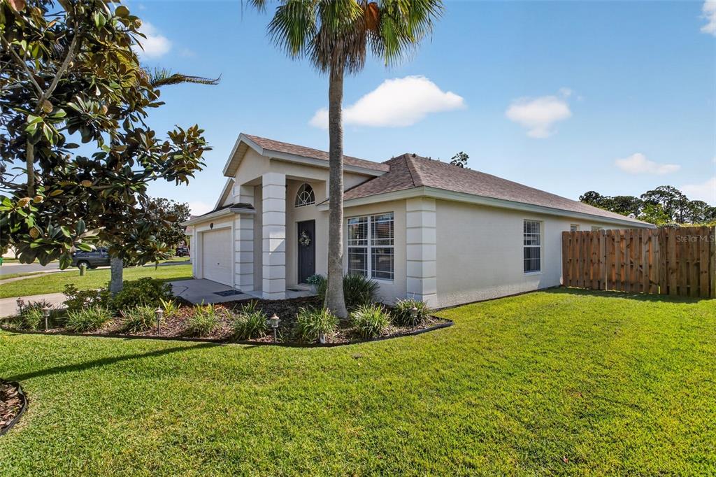 A single-story house with a beige stucco exterior, a palm tree, and a wooden fence — 1763 SUN GAZER DRIVE, ROCKLEDGE, FL