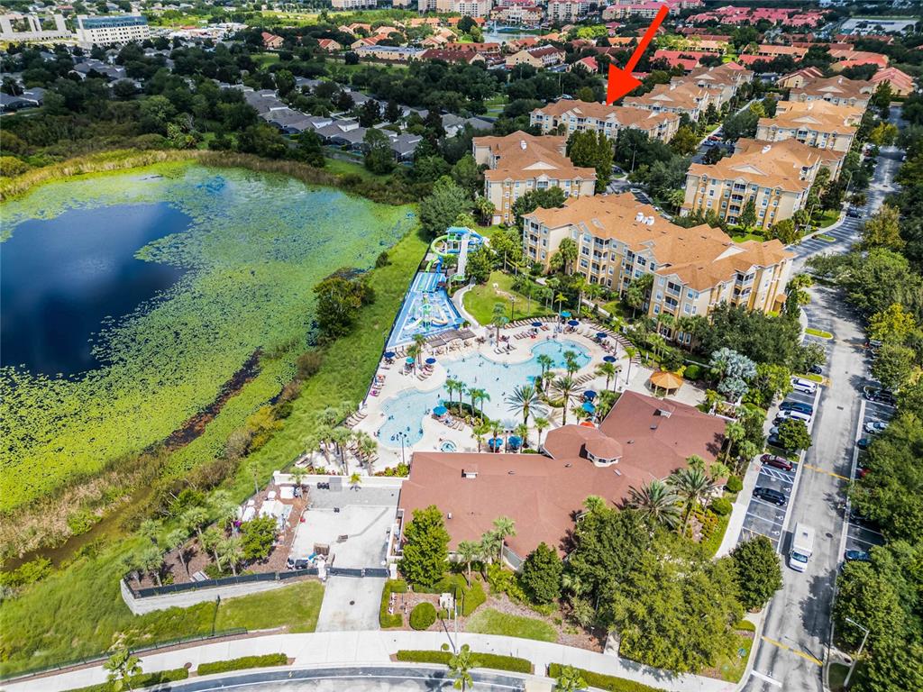 An aerial view shows a resort complex with a swimming pool, water slides, and buildings — 7671 COMROW STREET UNIT 202, KISSIMMEE, FL