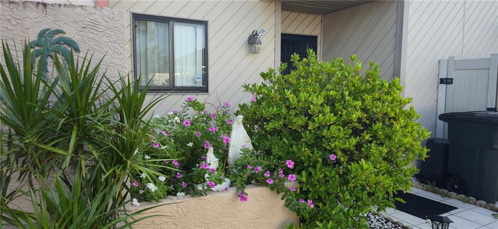 A residential exterior features a small garden bed with statues in front of a house — 2214 OAK WIND DRIVE, HOLIDAY, FL