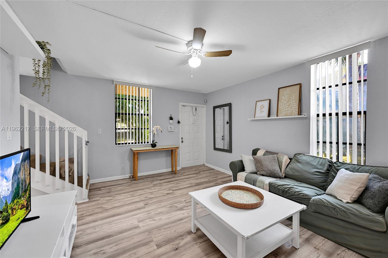 A living room features light wood-look flooring, a white coffee table, and a green sofa — 781 SE 1st Way # 79, Deerfield Beach FL 33441, DEERFIELD BEACH, FL