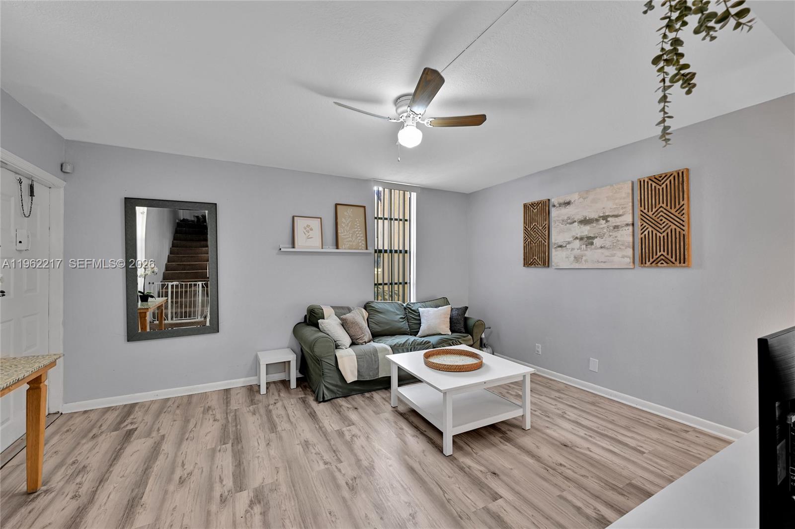 A living room features light gray walls, wood-look flooring, a green sofa, and a ceiling fan — 781 SE 1st Way # 79, Deerfield Beach FL 33441, DEERFIELD BEACH, FL