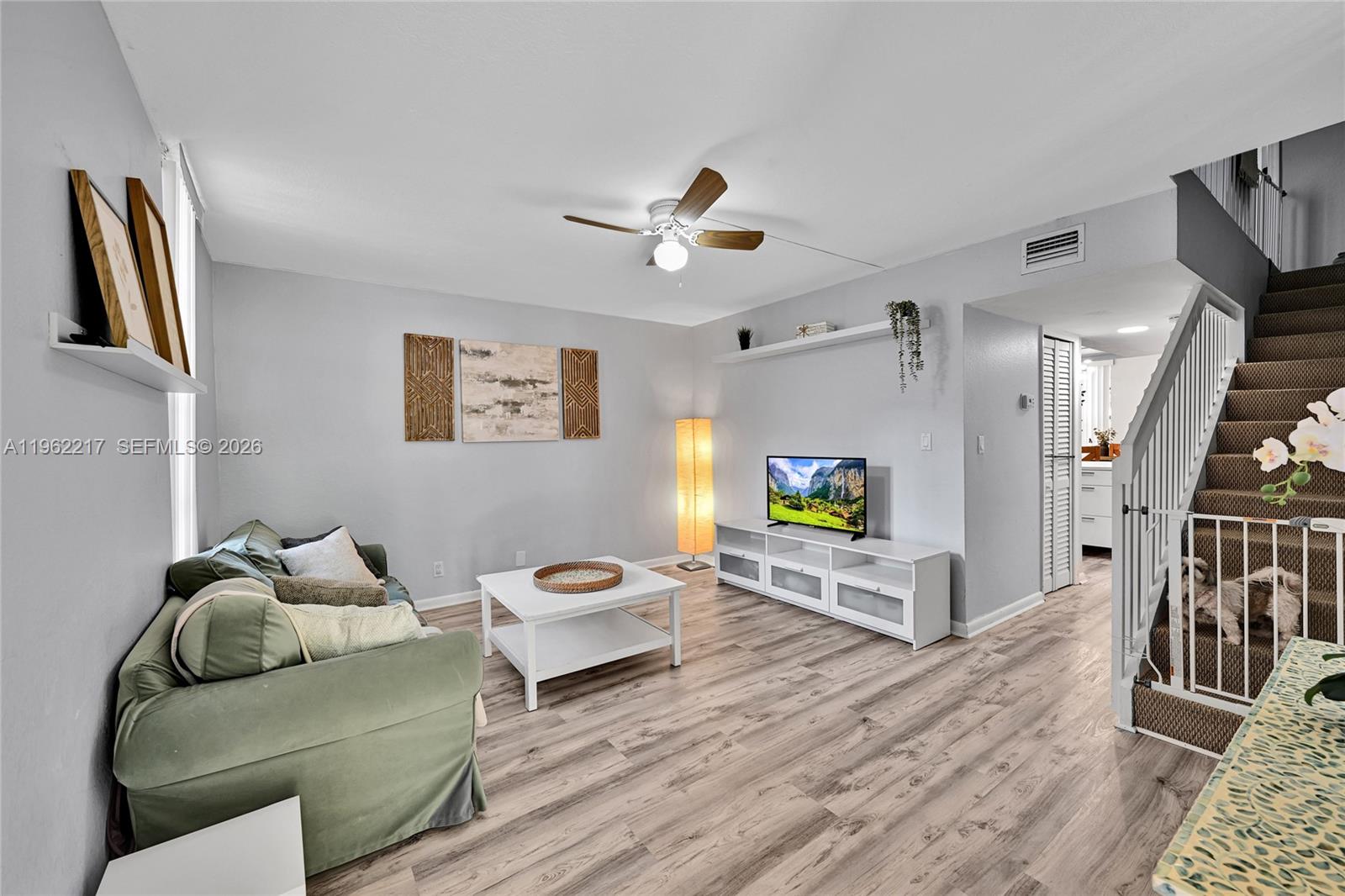 A living room features light wood-look flooring, a green sofa, a white coffee table, and stairs — 781 SE 1st Way # 79, Deerfield Beach FL 33441, DEERFIELD BEACH, FL