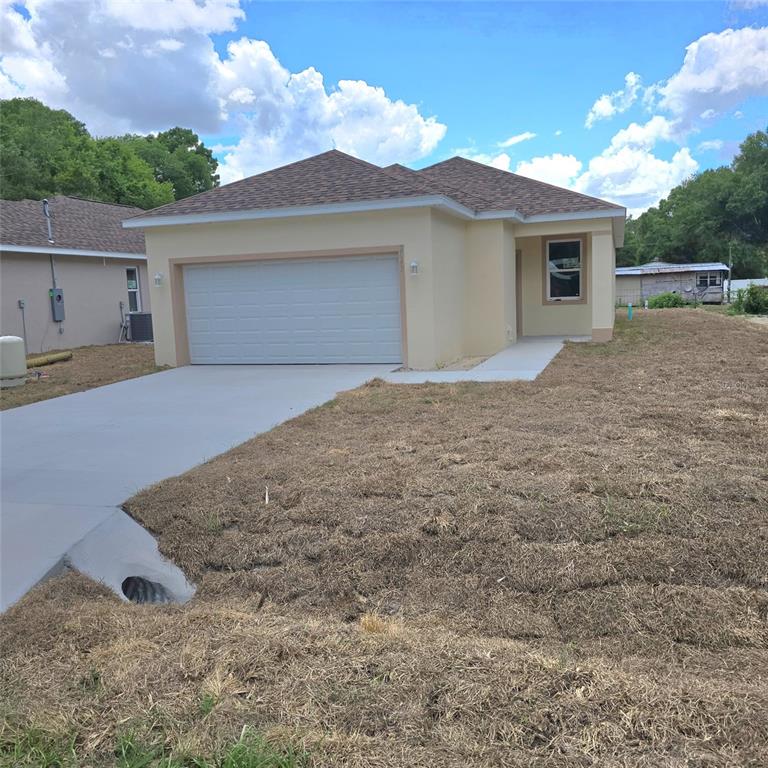 A newly constructed single-story house features a tan stucco exterior, a garage, and a driveway — 2043 MULLET ROAD, AUBURNDALE, FL