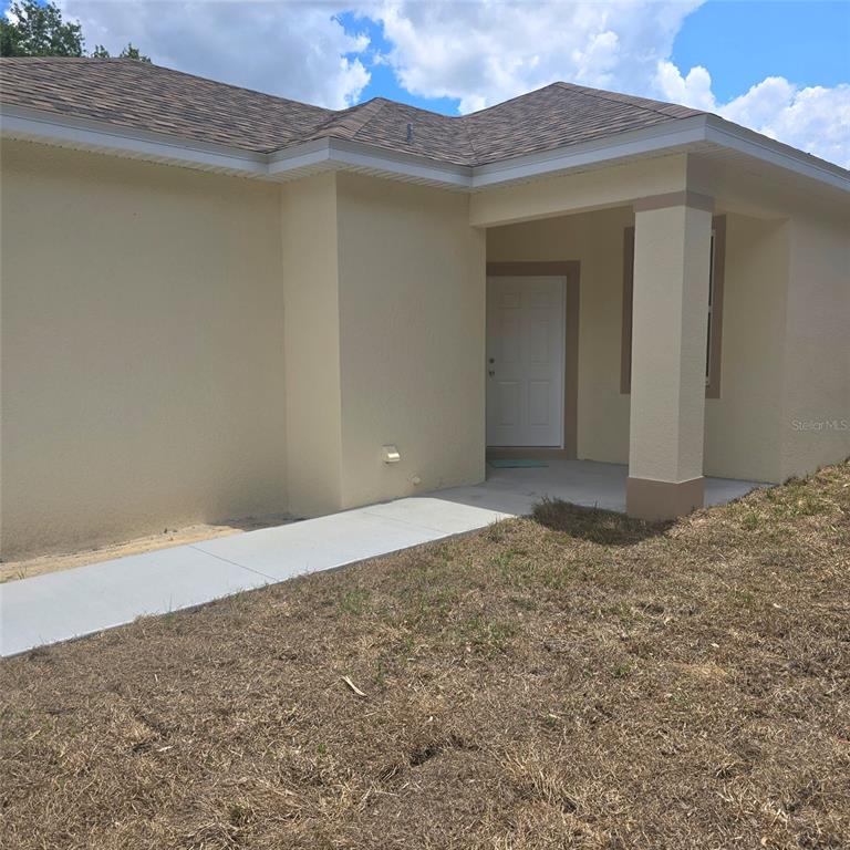 A beige stucco house exterior features a covered entryway with a white front door — 2043 MULLET ROAD, AUBURNDALE, FL